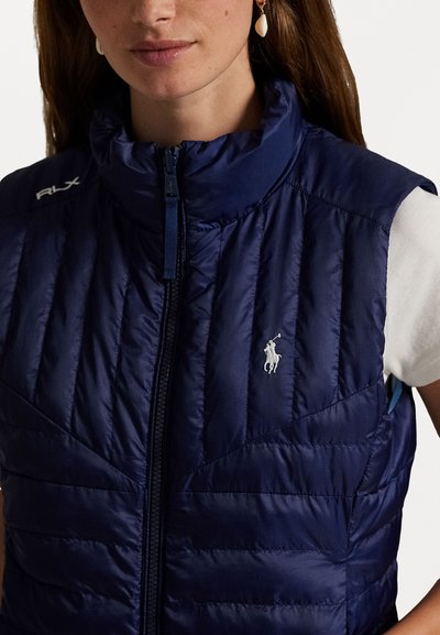Tumes puffer vest kõrge krae, kirbuga tekstuur ja eesmine lukustus. Omab väikest valget logo vasakul rinnapiirkonnas.