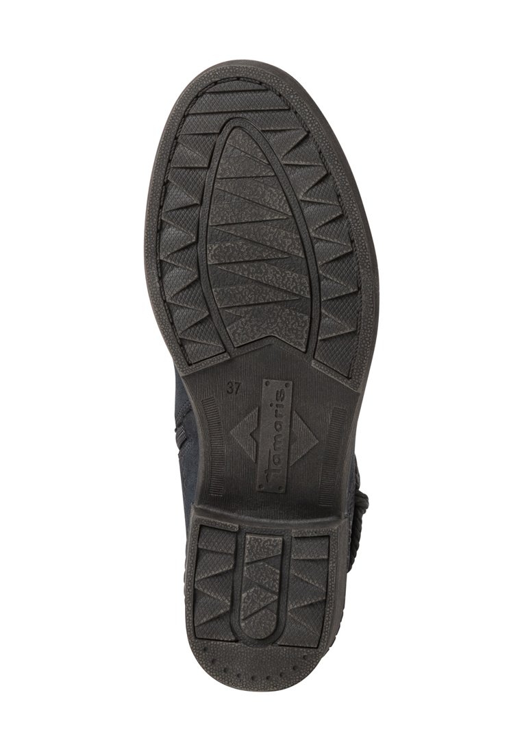 Semelle de chaussure en caoutchouc noir avec des motifs de grip texturés et un logo de marque. La semelle présente diverses formes triangulaires et circulaires pour une meilleure adhérence.