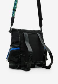 Black fabric bag with adjustable strap, featuring mesh pockets and blue accents. Includes multiple compartments and a zip closure.