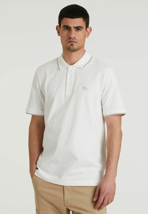 Witte polo met kleur, twee-knopen sluiting en contrasterende zwarte afwerking op de mouwen en de kraag. Heeft een klein logo op de borst.