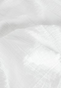 Tejido blanco con una superficie suave y texturizada, que presenta patrones sutiles y desiguales y una calidad ligera y etérea.