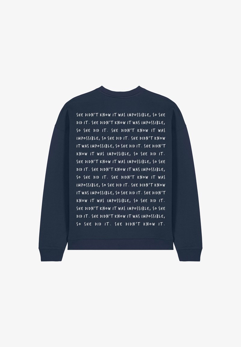 Felpa blu navy con maniche lunghe, caratterizzata da un testo bianco ripetitivo sul retro che parla di superare impossibilità.