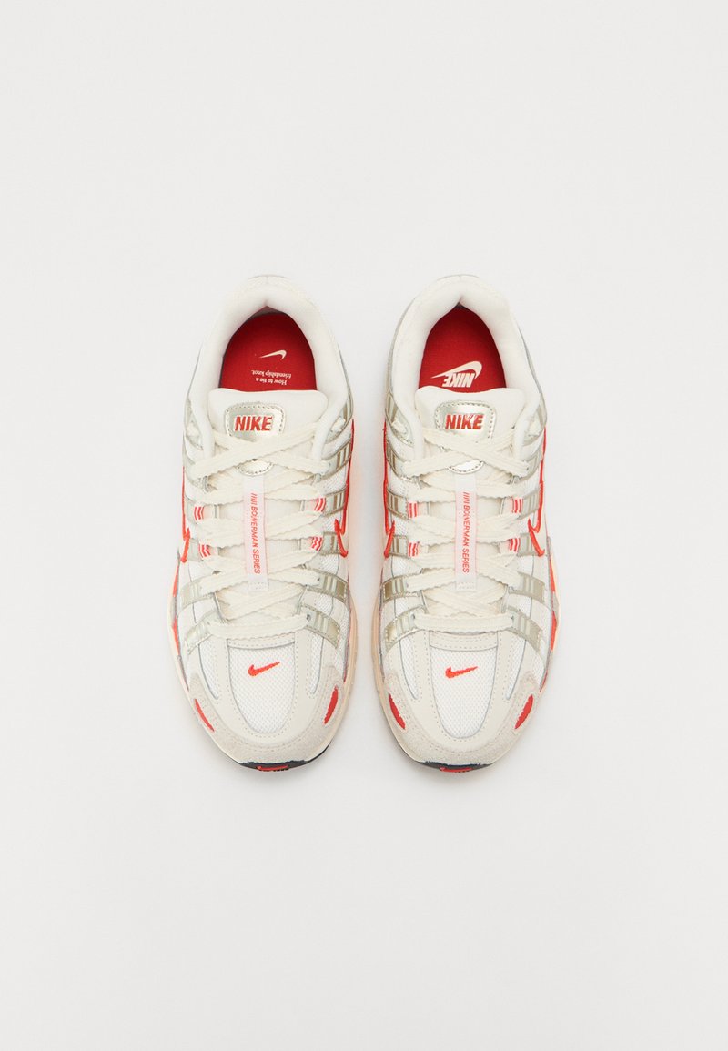 Nike Sneakers haben ein weißes Mesh-Obermaterial mit roten Akzenten, silbernen Überzügen und einer strukturierten Sohle. Schnürdesign mit einem gepolsterten Kragen.