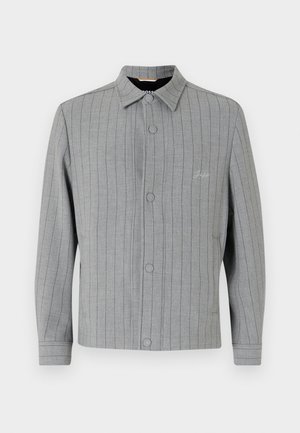 Jachetă gri cu dungi, cu nasturi pe față, guler clasic și buzunare laterale. Prezintă detalii subtile de coasere și un material texturat.