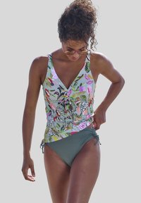 Wielokolorowa tankini z kwiatowym wzorem, z dekoltem w kształcie litery V i wiązaniem z przodu, połączona z jednolitymi, ciemnozielonymi majtkami bikini z regulowanymi wiązaniami po bokach.