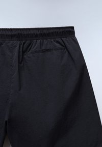 Pantaloncini neri con vita elastica e una singola tasca a filetto sul retro, mostrati da dietro su uno sfondo neutro.