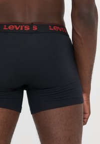 Schwarze Boxershorts mit enganliegender Passform, ausgestattet mit einem roten Levi's-Logo am Bund und glattem, elastischem Stoff.