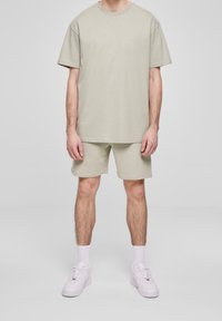 Jasno beżowa koszulka z krótkim rękawem o okrągłym dekolcie, zestawiona z dopasowanymi szortami. Uzupełniona białymi trampkami i skarpetkami do kostek.