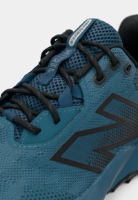 Kadar prikaza plave New Balance tenisice za trčanje s crnim vezicama, mrežastim gornjim dijelom i oznakom Infinity na jezičku.