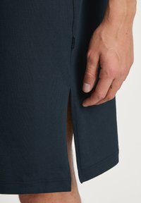 Navyblauwe katoenen shorts met zijsplit en klein logolabel. Heeft een gladde textuur en een recht afgeronde zoom.