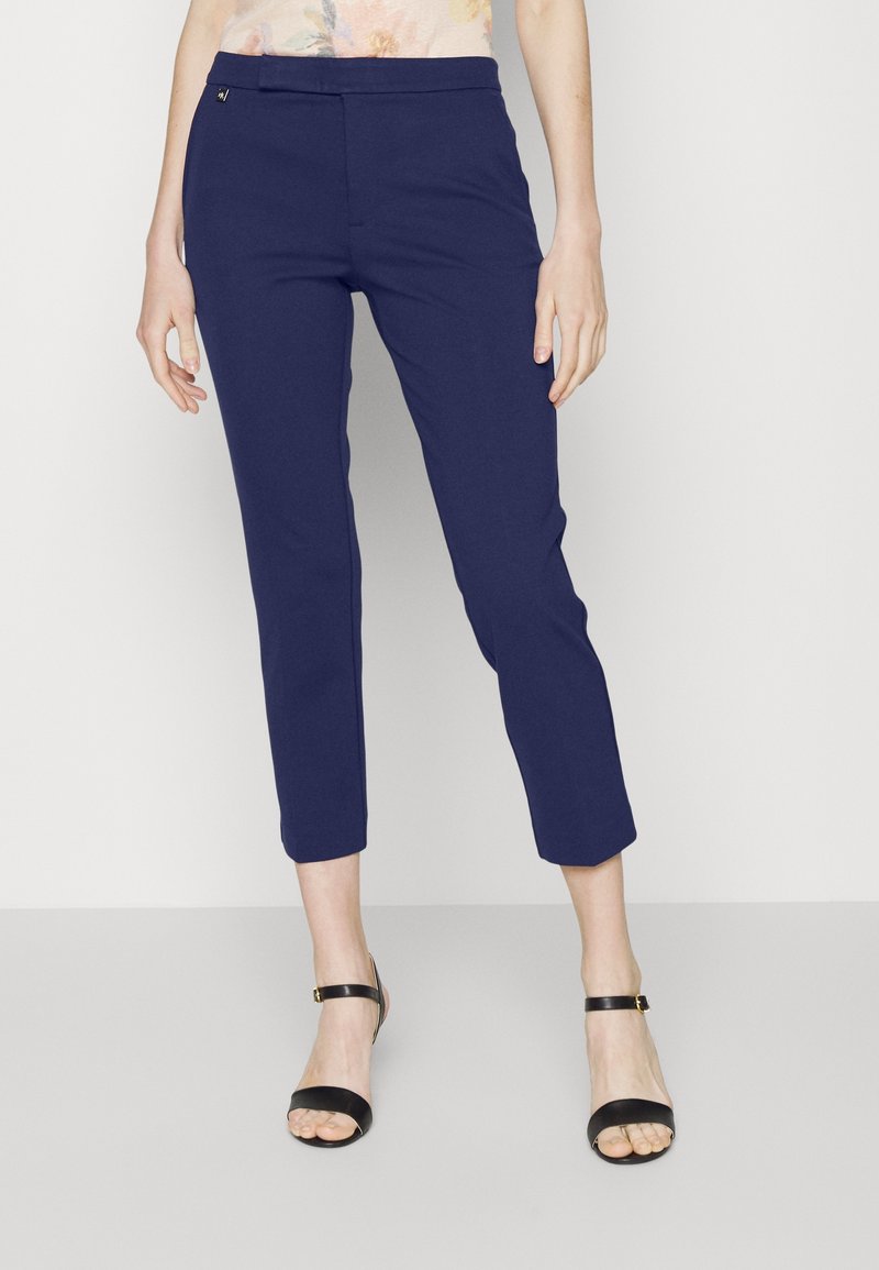 Mörkblå cropped byxor tillverkade av mjukt tyg med en slät textur och en subtil glans, med en åtsittande midja och ankellång nederkant.