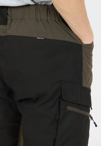 Cargo-broeken in olijfgroen en zwarte stof. Voorzien van een elastische tailleband, zijvak voor cargo en een zak met ritssluiting. Glad oppervlak, duurzame ontwerp.