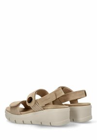 Sandalias beige con una tira texturizada y un botón decorativo. Cuentan con una suela acolchada y correas ajustables de velcro para mayor comodidad.
