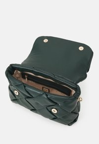 Sac à main en cuir matelassé vert avec une fermeture à pression magnétique, des accents en métal doré et un intérieur beige comprenant une poche zippée.