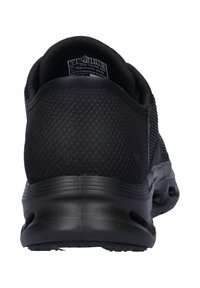 Scarpone sportivo nero con tomaia in rete sintetica, superficie testurizzata, collare imbottito e suola in gomma con fori di ventilazione.