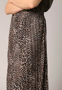 Jupe en imprimé léopard fabriquée à partir d'un tissu doux et léger. Dotée d'une taille élastique et d'un design fluide et drapé dans des tons bruns et noirs.