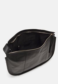 Melnas ādas rokassoma ar gludu tekstūru, kas aprīkota ar rāvējslēdzēja aizdari un plašu iekšpusi. Iekļauj iekšējo kabatu mazām lietām.