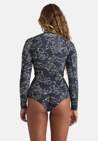 Dlouhý rukáv rash guard v námořnické modři s bílými květinovými vzory, s těsným střihem a kontrastním prošíváním podél švů.