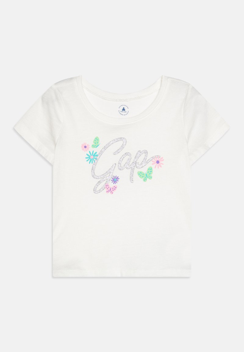 White cotton t-shirt with short sleeves, featuring "Gap" in silver glitter and colorful floral and butterfly graphics. Round neckline.