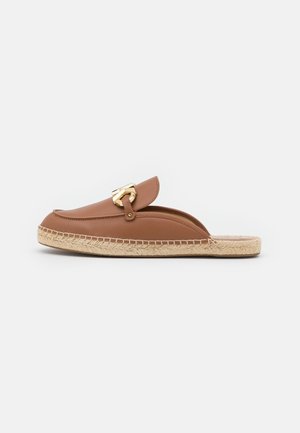 Brauner Leder-Slipper mit goldfarbenem Metallverschluss und gewebter Jute-Sohle vor weißem Hintergrund.