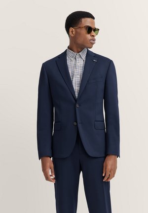 Marineblauer Anzug mit maßgeschneidertem Design, featuring einen geschlitzten Revers, zwei Knöpfen und Vordertaschen. Das Innenshirt hat ein helles Karomuster.