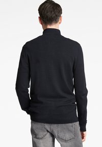 Dunkelblauer Pullover mit hohem Kragen, langen Ärmeln und geripptem Saum. Glatte Textur, taillierte Passform, geeignet für lässige Anlässe.