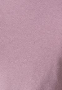 Vaaleanpunainen kangas, jossa on sileä, hieman teksturoitu pinta. Materiaali näyttää pehmeältä ja joustavalta, sopii arkivaatteisiin.