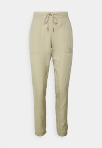 Beige bomullsmixbyxor med elastisk midja och dragsko, med sidofickor och en liten logotyp på vänstra låret.