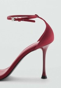 Sandal con tacco alto rosso, con finitura liscia, cinturino sottile alla caviglia e punta affusolata. Presenta un tacco a cono lucido e una suola testurizzata.