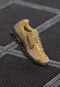 Nike Air Max sneaker in yellow with a textured mesh upper, sleek design, black accents, and a visible air cushioning sole.