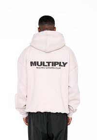 Sudadera de gran tamaño en gris claro con un gran logo negro "MULTIPLY" en la parte trasera, con capucha ajustable y puños acanalados.