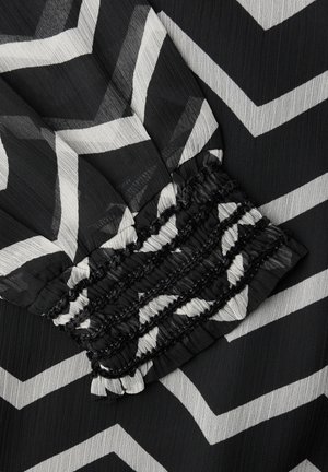 Černo-bíle žebrovaná látka se zřaseným elastickým manžetovým detailem.