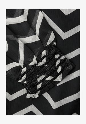 Tissu à motif zigzag noir et blanc avec un détail de poignet froncé élastique.