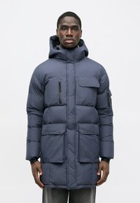 Ναυτικό μπλε επενδυμένο παρκά με ψηλό γιακά, κουκούλα, πολλαπλές τσέπες και φερμουάρ. Απαλή υφή και ελαφρύ σχέδιο.