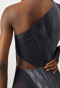 Asymmetrisch zwart bodysuit met een soepele textuur, voorzien van een uitsnede aan de zijkant en subtiele grijze patronen langs de rug.
