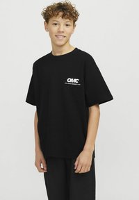 Juodas medvilnės marškinėliai trumpomis rankovėmis su baltu logotipu "OMC" ir tekstu "OFF-TRACK MEMBERS' CLUB" kairėje krūtinės pusėje.