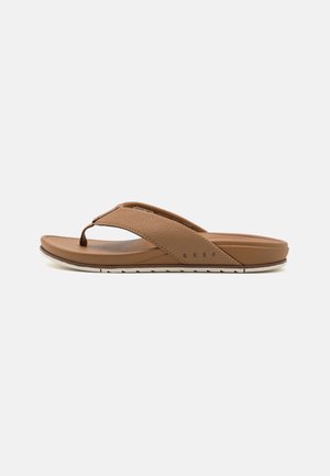Brown flip-flop sandal with a textured strap, soft footbed, and a flexible sole. Features a minimal design and contrasting white stitching.