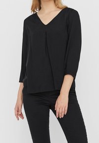 Schwarze Bluse mit V-Ausschnitt, Dreiviertelärmeln und Falten-Detail vorne. Hergestellt aus glattem Stoff, mit einer lockeren, entspannten Passform.