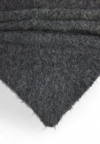 Tela de fieltro gris carbón, que muestra una textura suave con una superficie ligeramente difusa. Los bordes son sin rematar y de forma triangular.