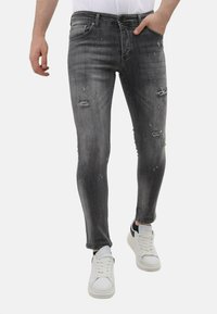 Grijze denim jeans met een slim fit, versleten details, kleine scheuren en een vervaagde afwerking, gecombineerd met witte sneakers.
