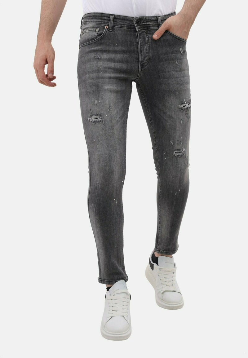 Grijze denim jeans met een slim fit, versleten details, kleine scheuren en een vervaagde afwerking, gecombineerd met witte sneakers.