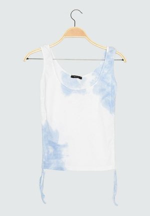 Biały i jasnoniebieski bezrękawnik z efektem tie-dye, z zaokrąglonym dekoltem, wiszący na drewnianym wieszaku na jednolitym jasnym tle.