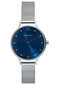 Reloj Skagen con correa de malla de plata y esfera azul, con marcadores de hora plateados, dos agujas plateadas y el nombre de la marca situado por encima del centro.