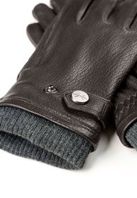 Svarta läderhandskar med en texturerad yta, med en stickad grå manschett och metallaccenter för stängning. Detaljerad sömnad längs kanterna.