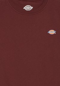 Kvaišnių spalvos medvilninis marškinėliai su apvalia iškirpte ir mažyte mėlyna bei geltona "Dickies" logotipu kairėje krūtinės pusėje. Minkšta tekstūra.