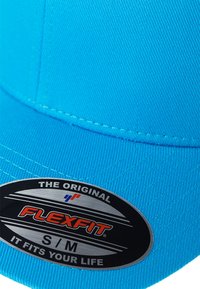 Light blue snapback cap with a textured fabric, featuring a black circular label that reads “FLEXFIT S/M” and “THE ORIGINAL.”