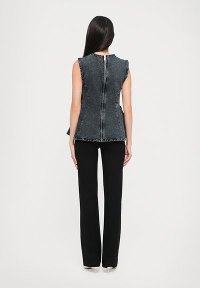 Denim bezpiegu top ar pieguļošu dizainu, saplīsušām malām un aizmugures rāvējslēdzēju. Apvienots ar melnām, platām biksēm un norādītas papēžiem.