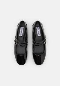 Pantofi Mary Jane din piele sintetică neagră cu două bretele ajustabile cu catarame, vârf pătrat și interior neted. Include eticheta "STEVE MADDEN".