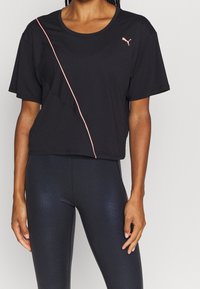 Camiseta atlética negra de manga corta, con una raya diagonal rosa y un logo de Puma en el pecho, fabricada con un material ligero.