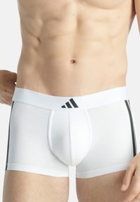Vita boxershorts med en tajt passform, med en svart randig accent och ett elastiskt midjeband med Adidas-logotypen. Slät tygtextur.